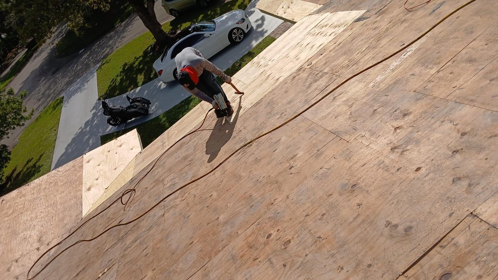 Roofer nailing new plywood decking on a residential re-deck