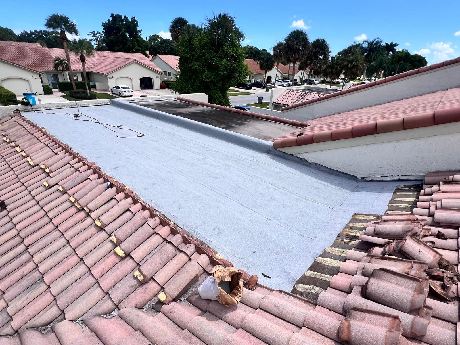 Freshly coated flat roof deck framed by pink barrel tile slopes