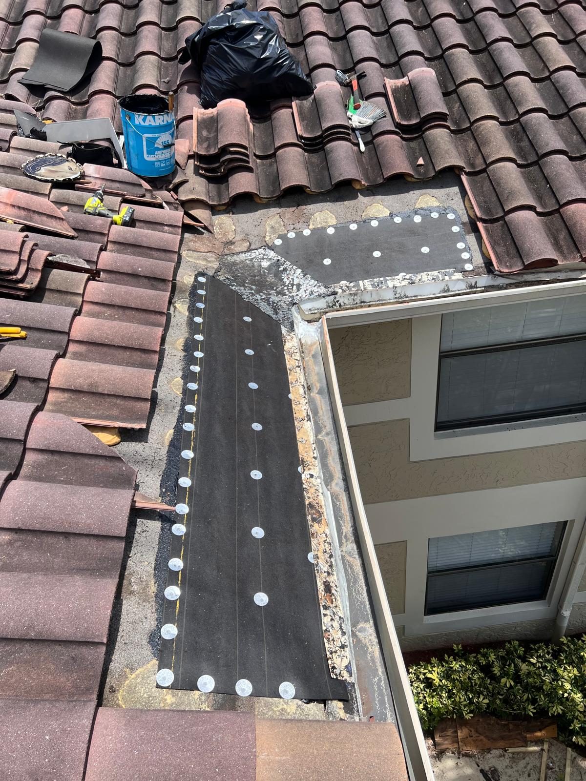 Low-slope roof section with new base sheet and plate fasteners beside barrel tile