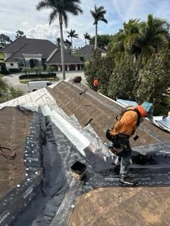 Crew member installing valley metal flashing over roof underlayment